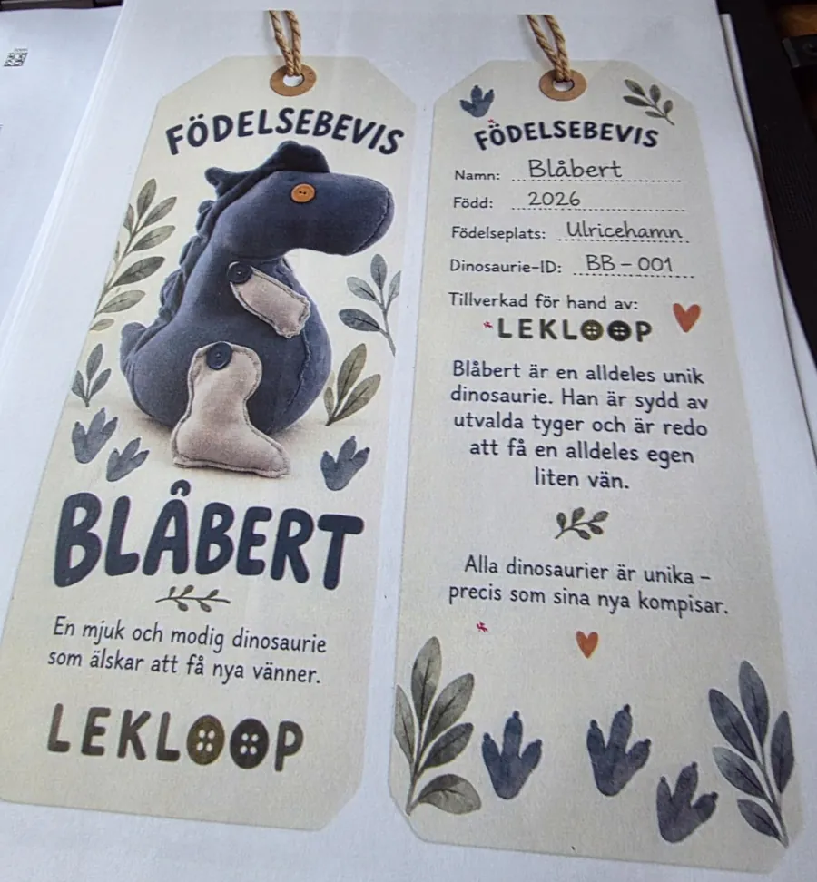 Födelsebevis för Blåbert, en mörkblå dinosaurie. Född 2026 i Ulricehamn, dinosaurie-ID BB-001, tillverkad för hand av Lekloop