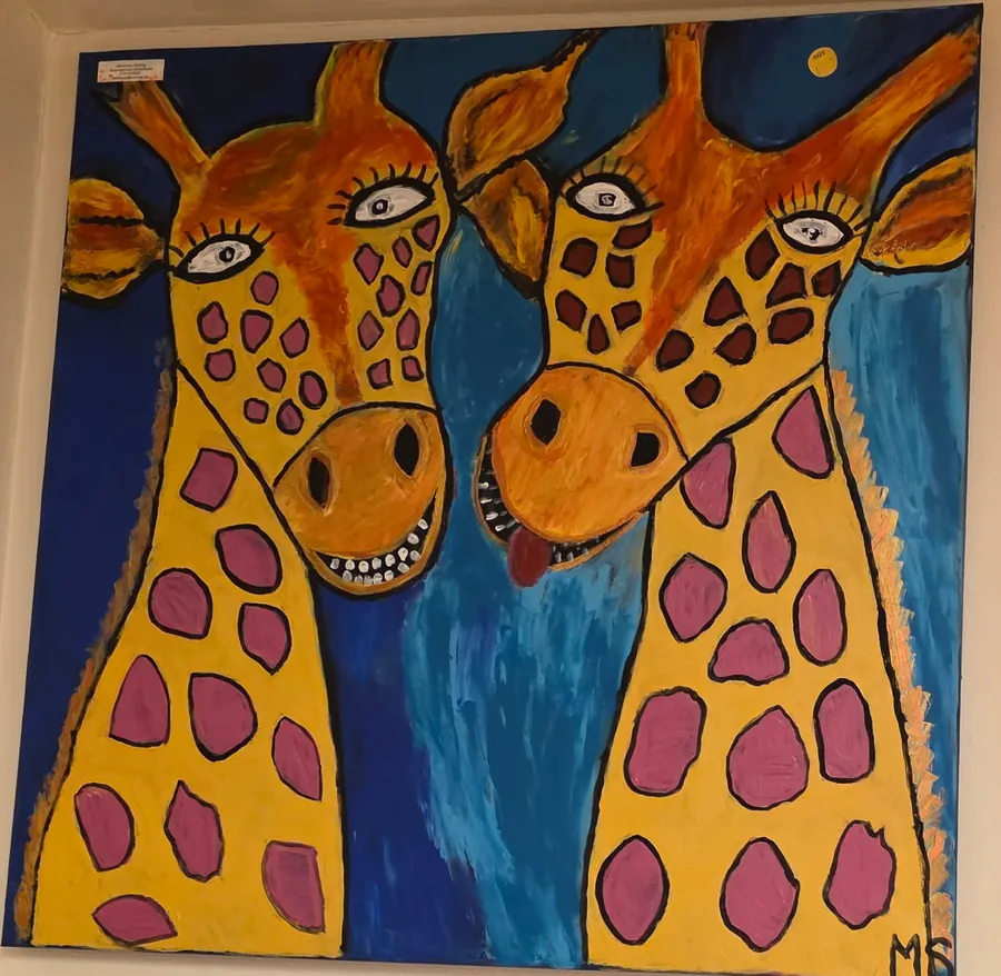 Stor tavla med två glada giraffer, den ena räcker ut tungan, mot en blå bakgrund
